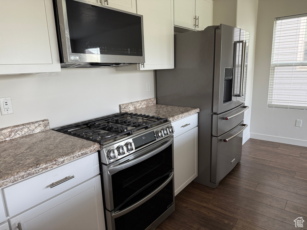 Kitchen with stainless steel appliances, dark wood finished floors, light countertops, and white cabinets