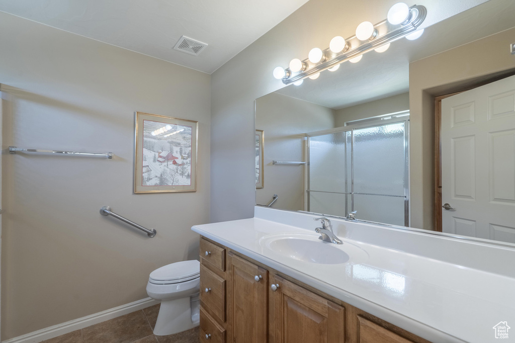Full bath with an enclosed shower, toilet, vanity, baseboards, and tile patterned flooring