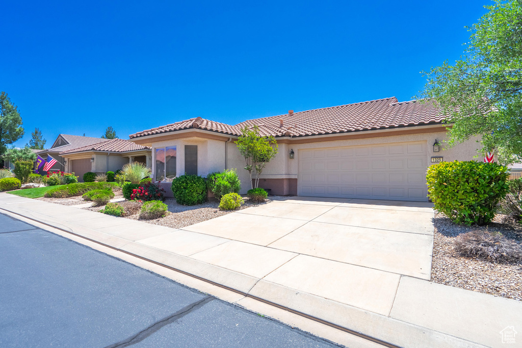 View of front of house with a tile roof, a garage, driveway, and stucco siding