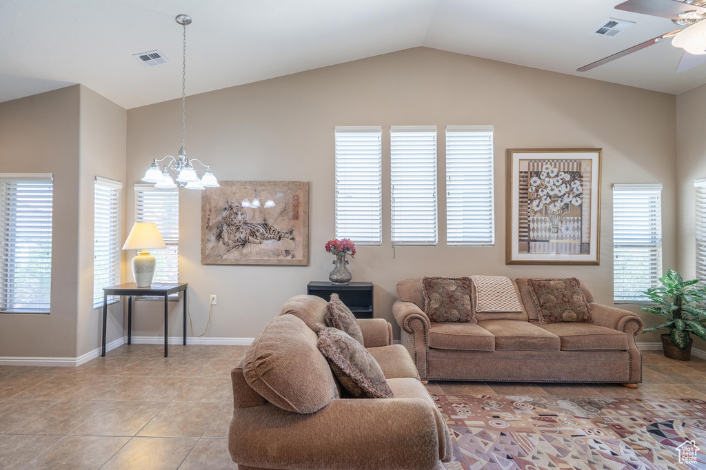 Living area with a chandelier, a ceiling fan, vaulted ceiling, baseboards, and light tile patterned floors
