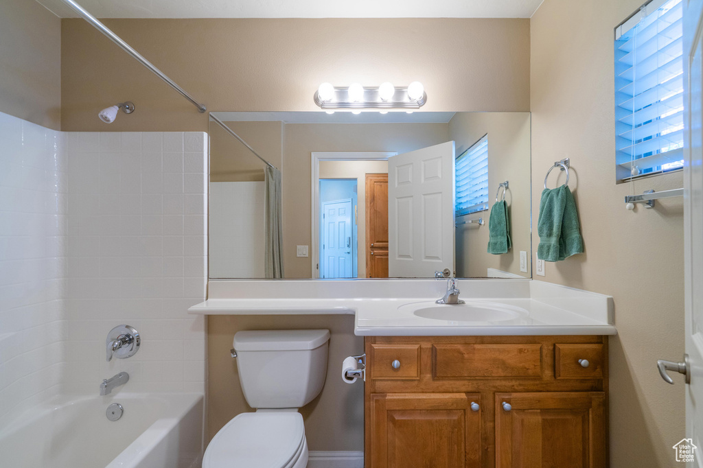 Bathroom featuring healthy amount of natural light, toilet,  shower combination, and vanity
