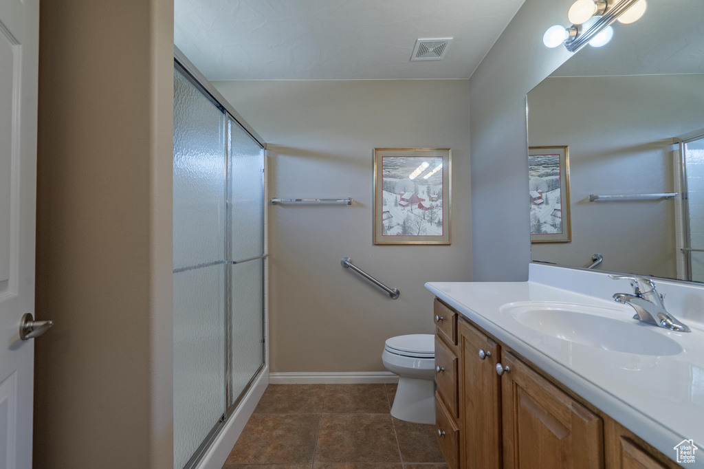 Full bathroom with a stall shower, toilet, vanity, and tile patterned flooring