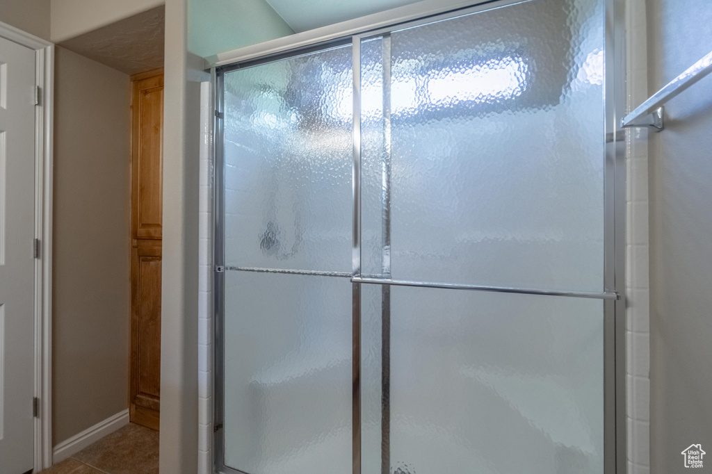 Bathroom featuring a shower stall, tile patterned floors, and baseboards
