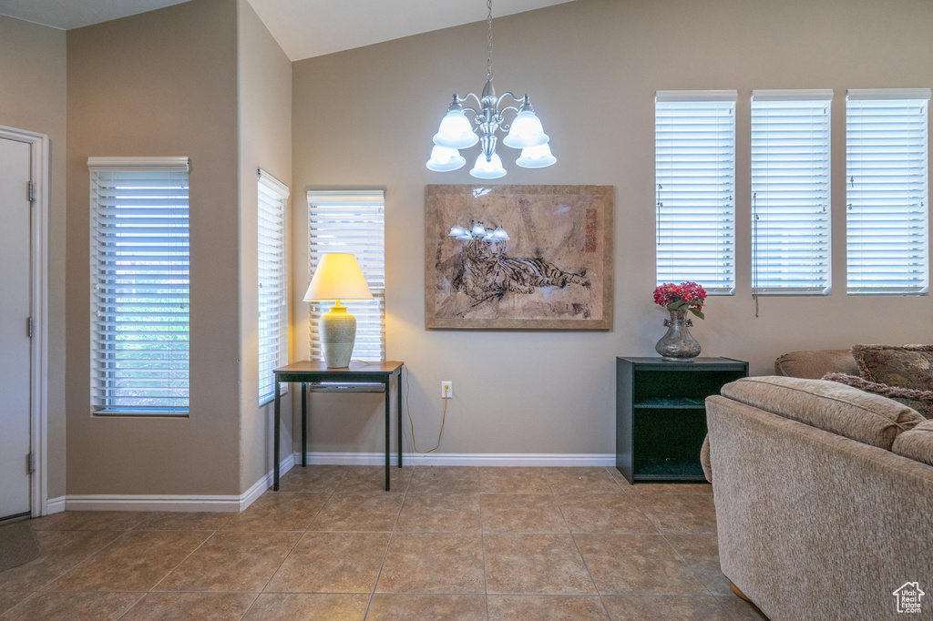 Tiled entryway featuring a chandelier, vaulted ceiling, and baseboards