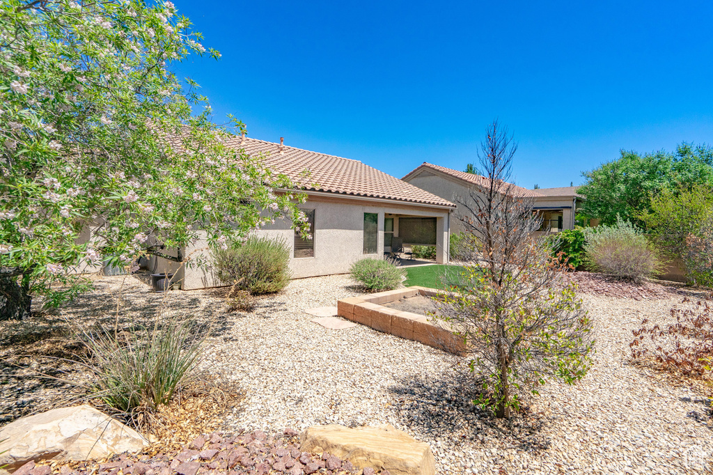 Back of property featuring stucco siding, a tile roof, and a patio