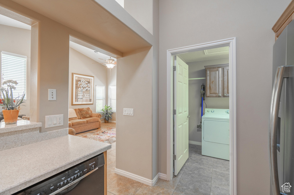 Kitchen featuring washer / dryer, black dishwasher, light tile patterned floors, light countertops, and freestanding refrigerator