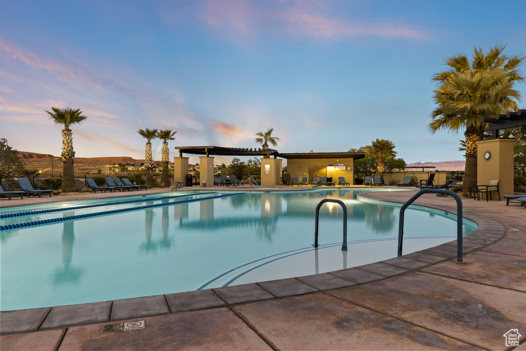 Pool at dusk featuring a community pool and a patio area