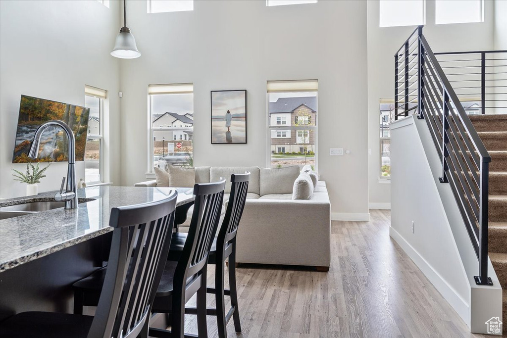 Dining room with stairway, a towering ceiling, light wood finished floors, and baseboards