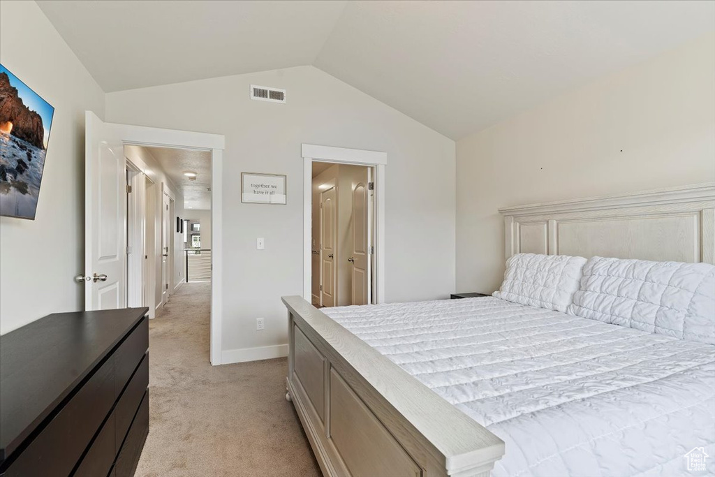 Bedroom featuring light carpet, vaulted ceiling, visible vents, and baseboards