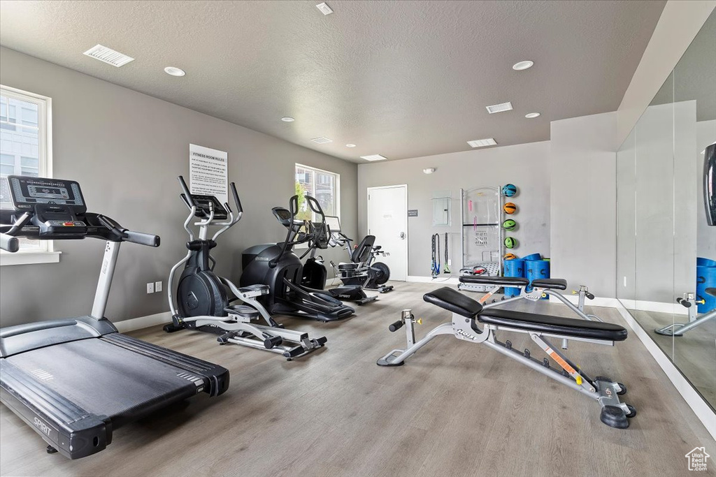 Workout area featuring recessed lighting, wood finished floors, visible vents, baseboards, and a textured ceiling