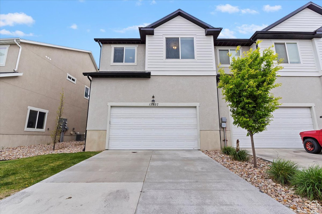 View of front facade with stucco siding, driveway, and a garage
