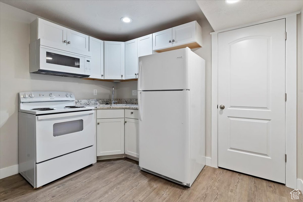 Kitchen featuring white cabinetry, white appliances, and light wood-style flooring