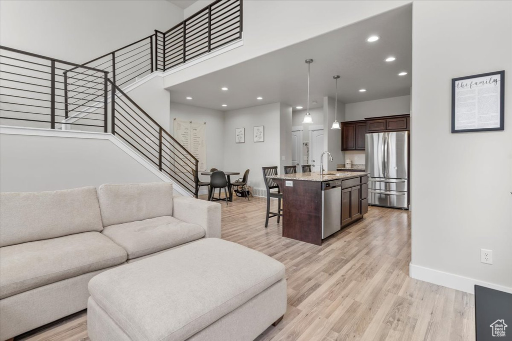 Living area featuring recessed lighting, baseboards, light wood finished floors, and stairs