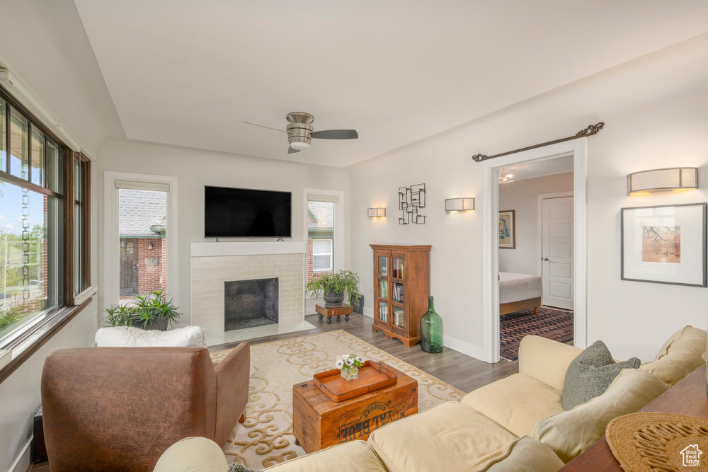 Living room with baseboards, a ceiling fan, wood finished floors, and a fireplace