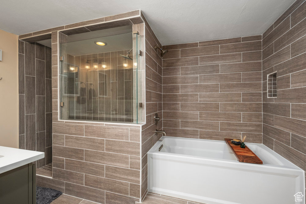 Full bath with vanity, a bathing tub, and tiled shower