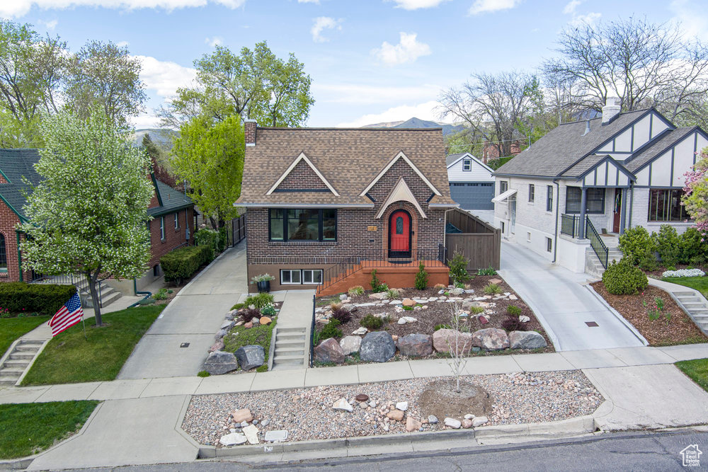 English style home with brick siding, stairway, driveway, and a shingled roof