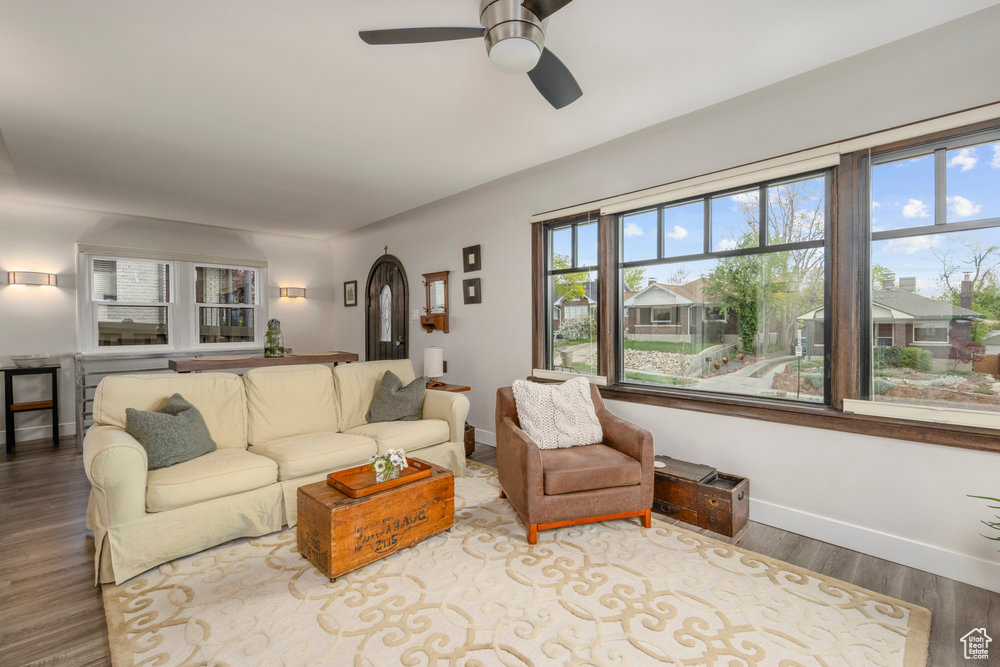 Living room featuring arched walkways, ceiling fan, baseboards, and wood finished floors