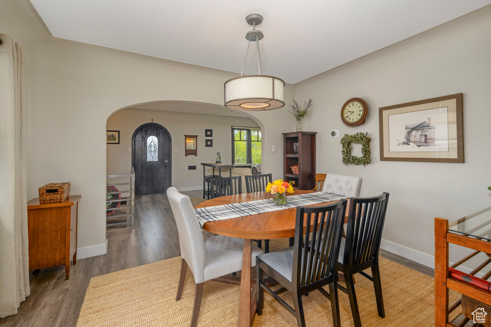 Dining area with baseboards, arched walkways, and light wood-style floors