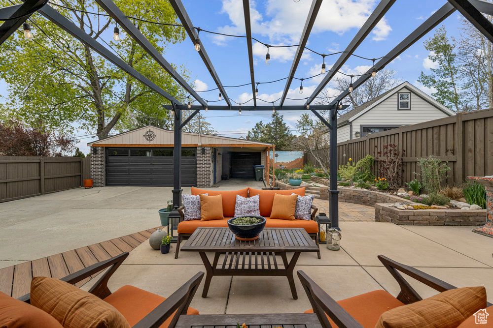 View of patio featuring an outdoor structure, a detached garage, a fenced backyard, and an outdoor living space