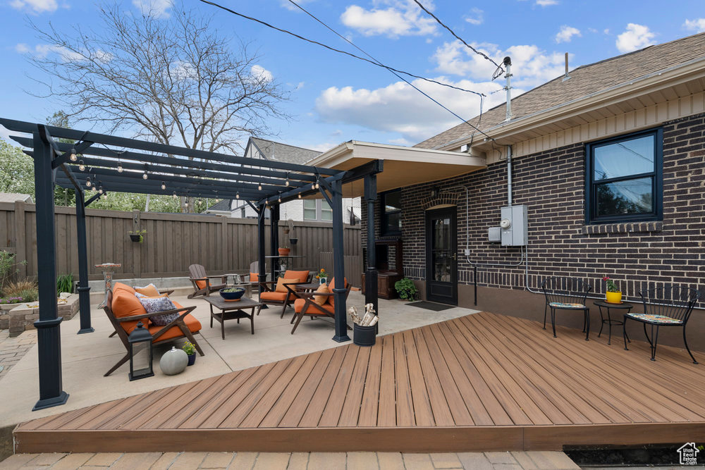 Wooden terrace with fence, a pergola, and an outdoor fire pit