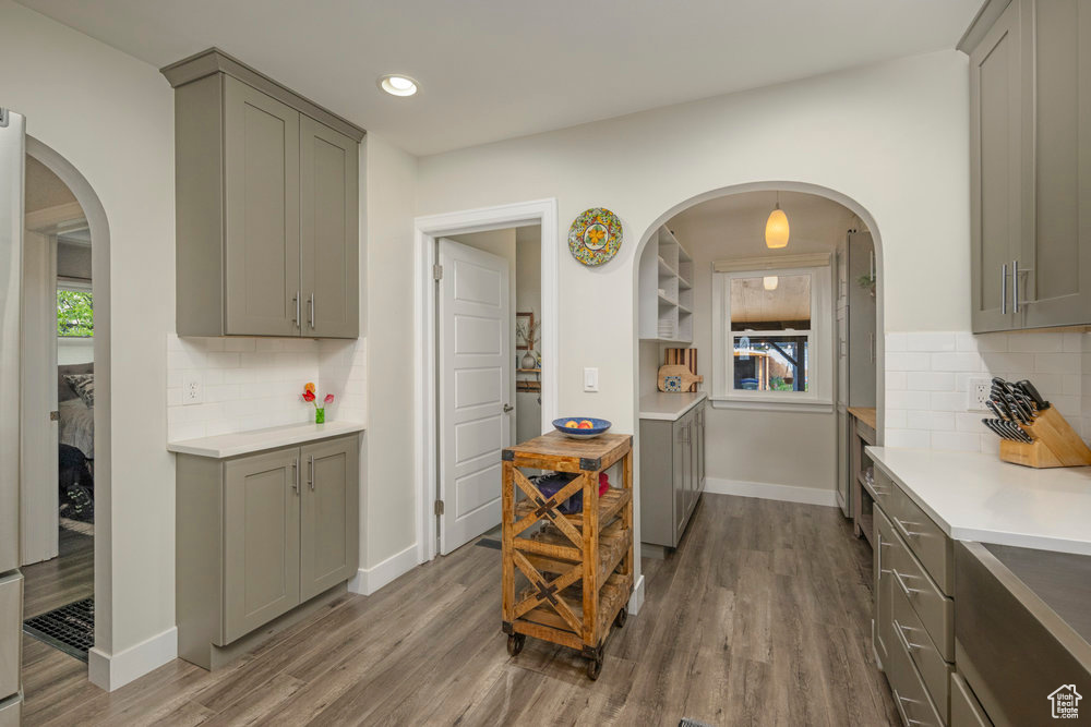 Kitchen with light countertops, wood finished floors, gray cabinetry, and tasteful backsplash