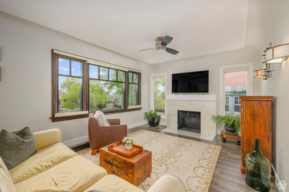 Living room with wood finished floors, a ceiling fan, baseboards, and a healthy amount of sunlight