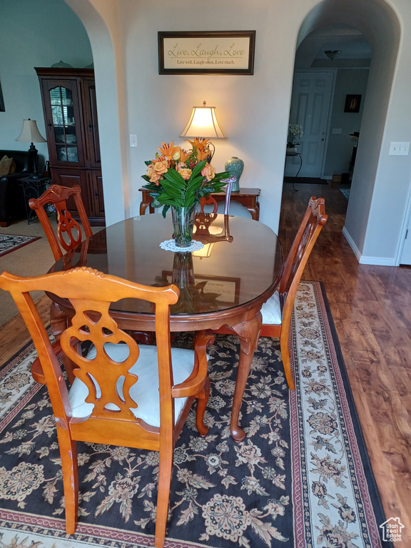 Dining space with wood finished floors, baseboards, and arched walkways