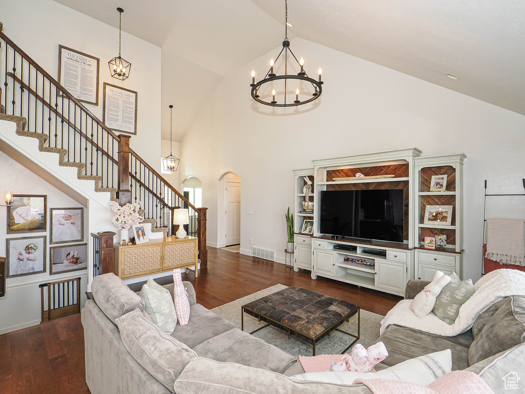Living area with dark wood-style floors, visible vents, arched walkways, and a chandelier
