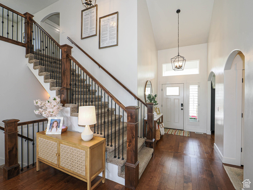 Entryway featuring wood-type flooring, arched walkways, baseboards, and high vaulted ceiling