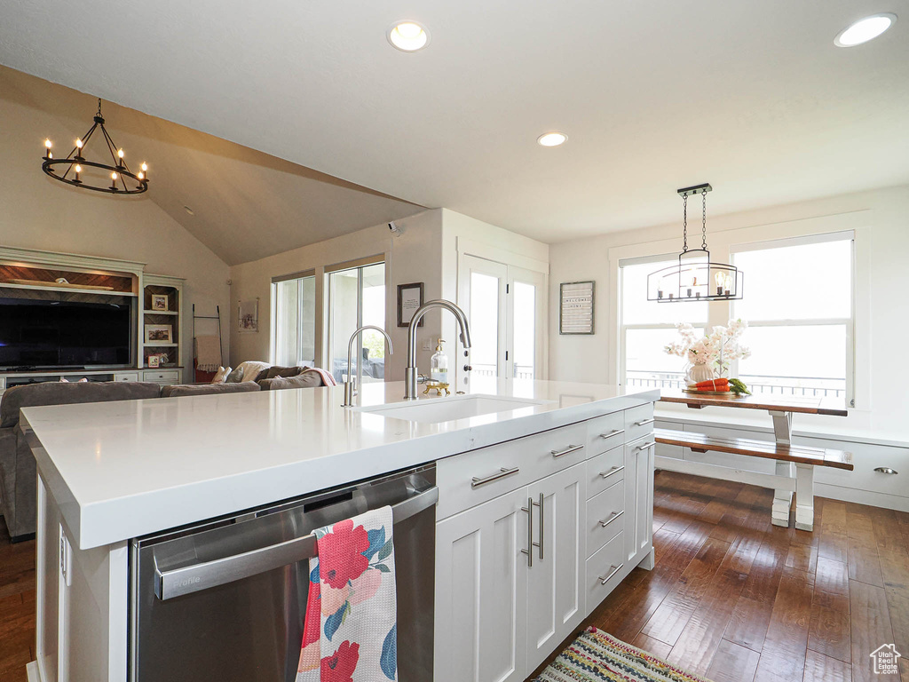 Kitchen featuring stainless steel dishwasher, a sink, dark wood-style flooring, open floor plan, and a chandelier