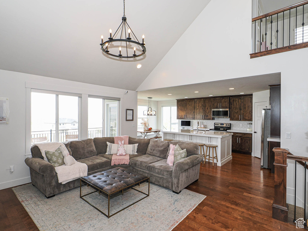 Living room featuring a chandelier, high vaulted ceiling, dark wood-style flooring, and recessed lighting