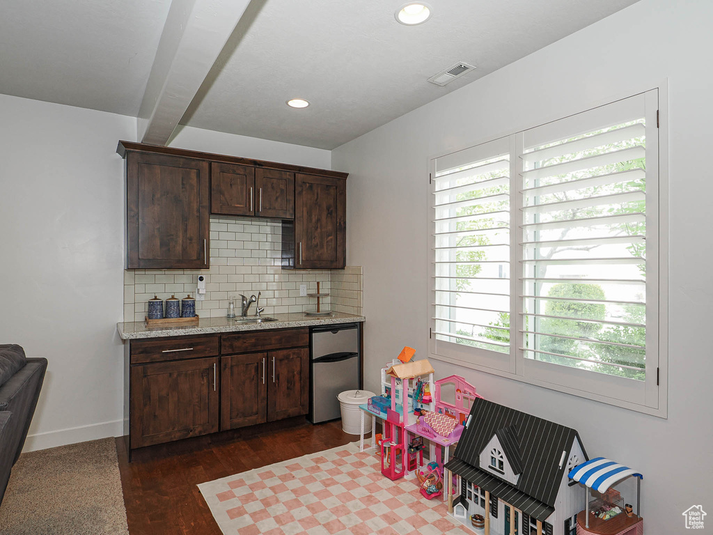 Kitchen with a sink, a healthy amount of sunlight, dark brown cabinets, fridge, and backsplash