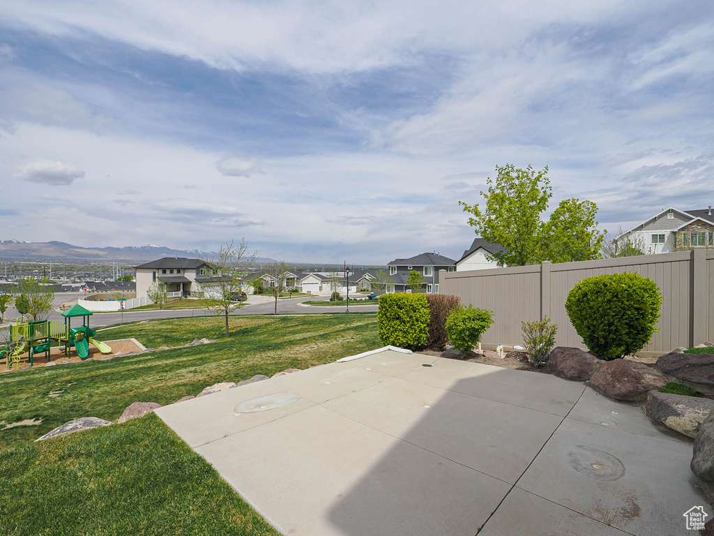 View of patio with fence, a residential view, a playground, and a mountain view