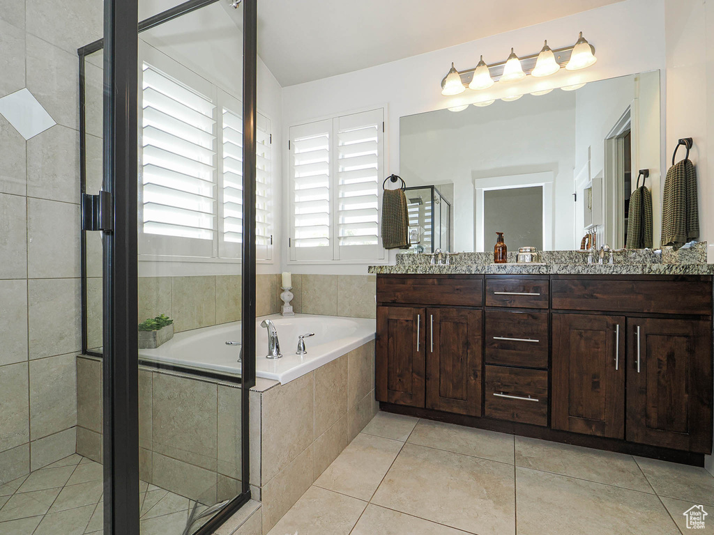 Full bath featuring tile patterned floors, a sink, double vanity, a shower stall, and a garden tub