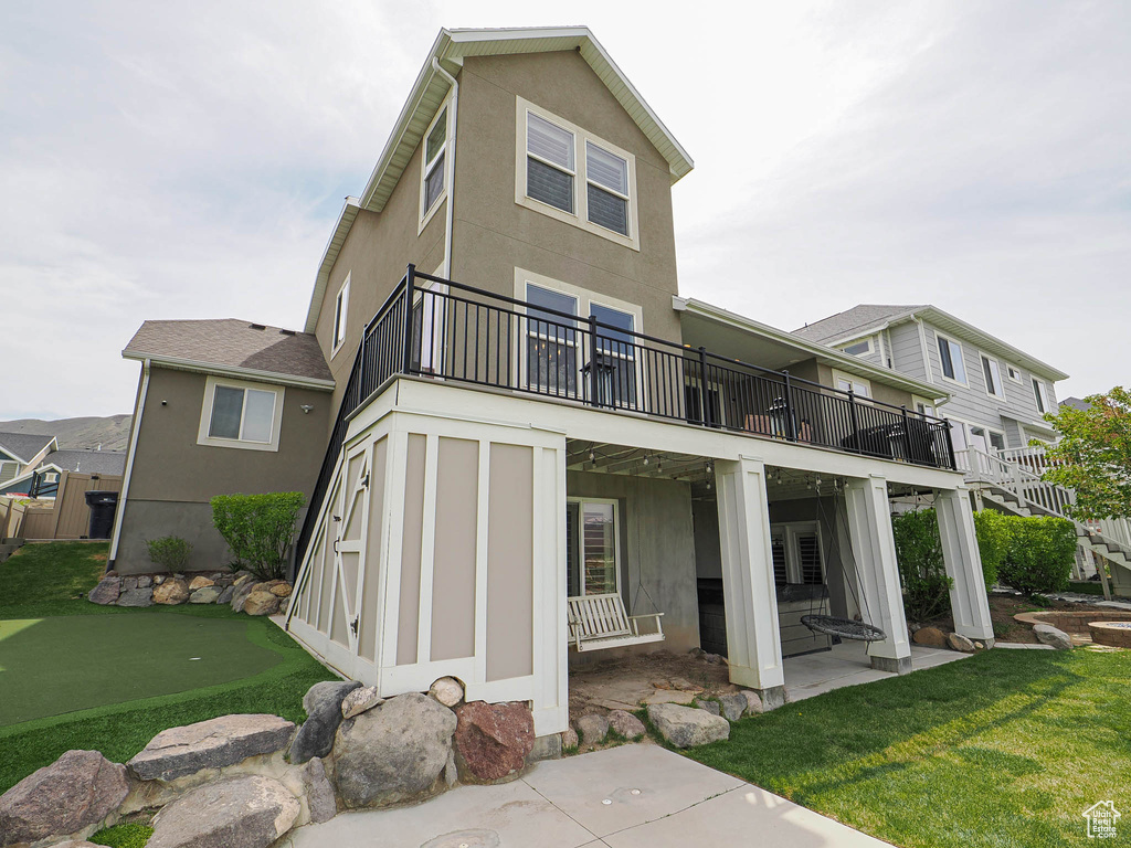 Back of house featuring stairway, a balcony, a yard, stucco siding, and a patio area