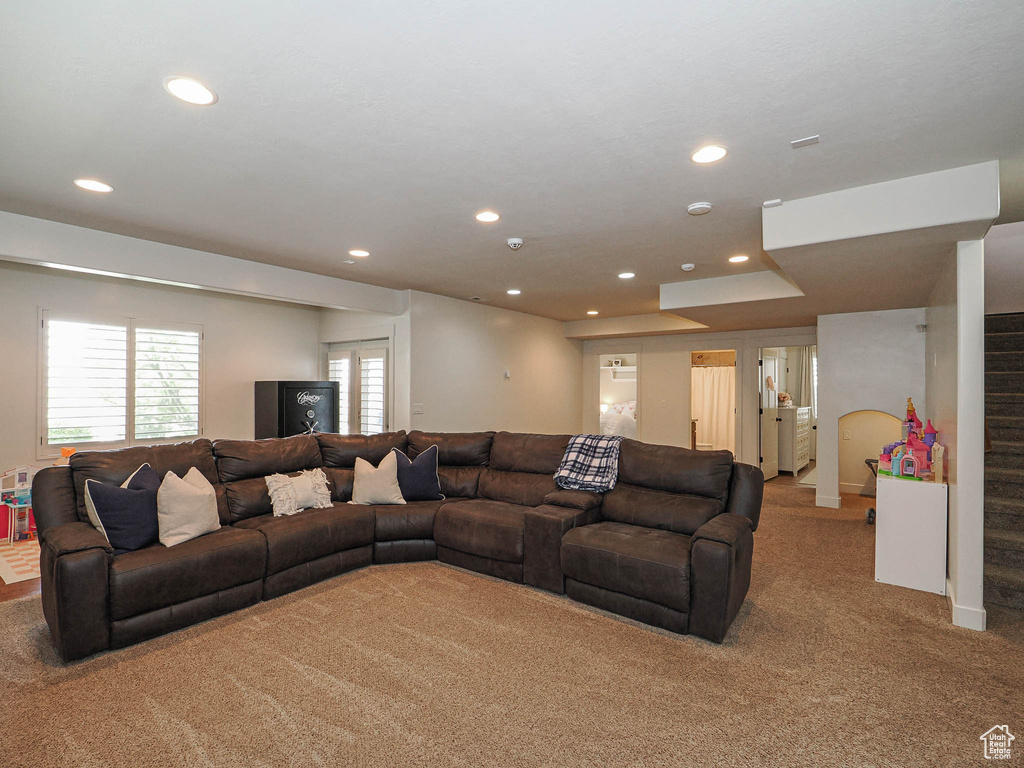 Living area with carpet flooring, recessed lighting, and stairway