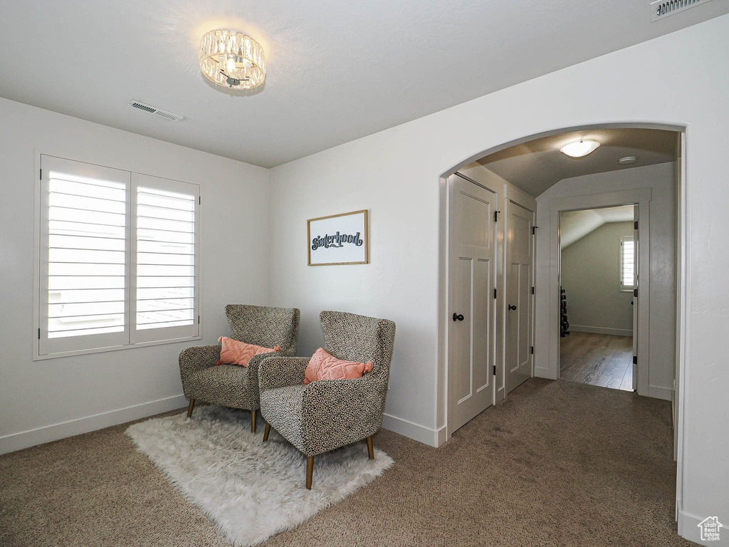 Sitting room with arched walkways, carpet floors, visible vents, and baseboards