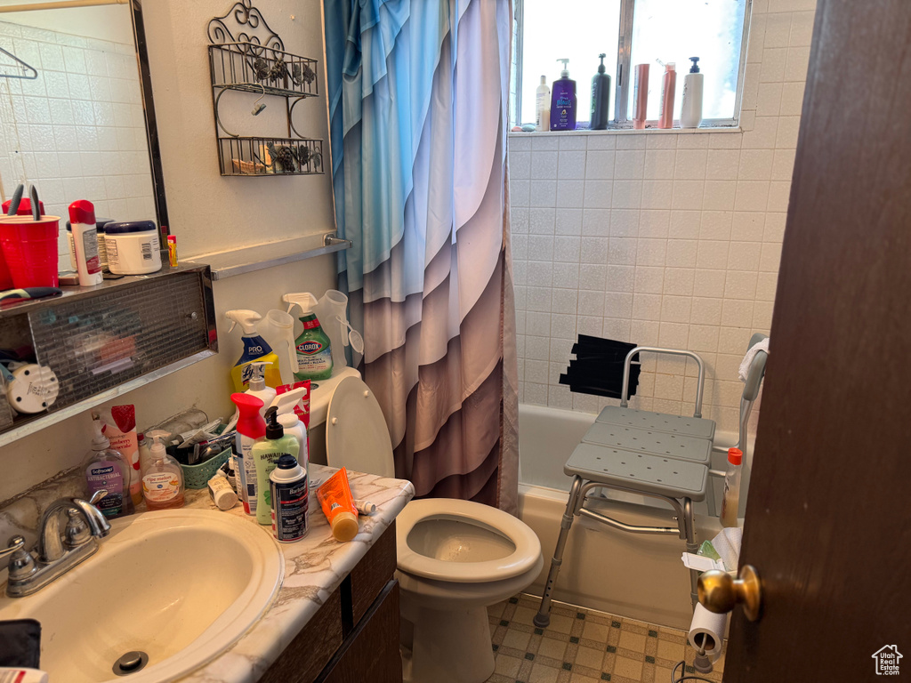 Bathroom featuring tile patterned floors, vanity, shower / bathtub combination with curtain, and toilet