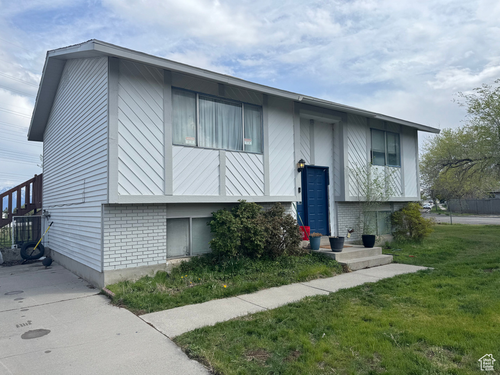Bi-level home with a front lawn and brick siding