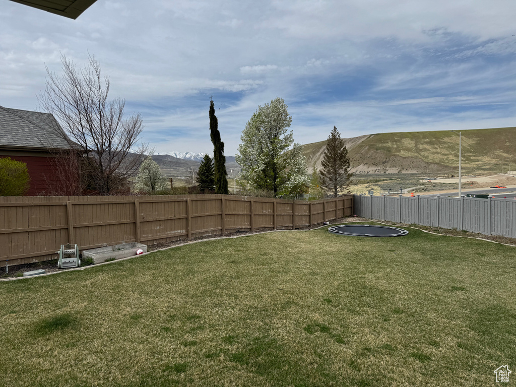 View of yard with a mountain view and fence