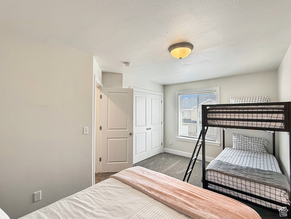 Bedroom with baseboards, a closet, a textured ceiling, and carpet