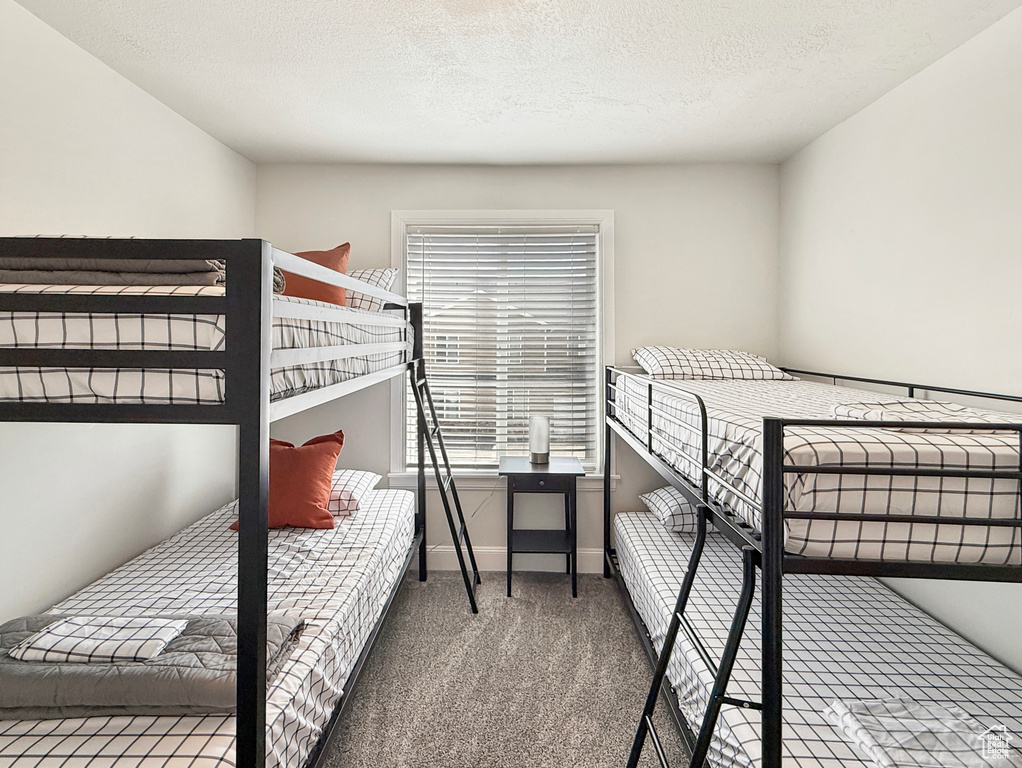 Carpeted bedroom featuring a textured ceiling and baseboards