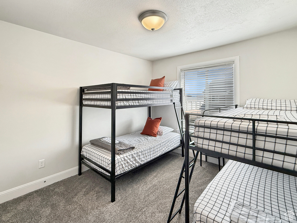 Bedroom with carpet floors, a textured ceiling, and baseboards