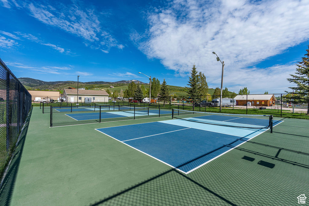 View of tennis court featuring fence and a mountain view