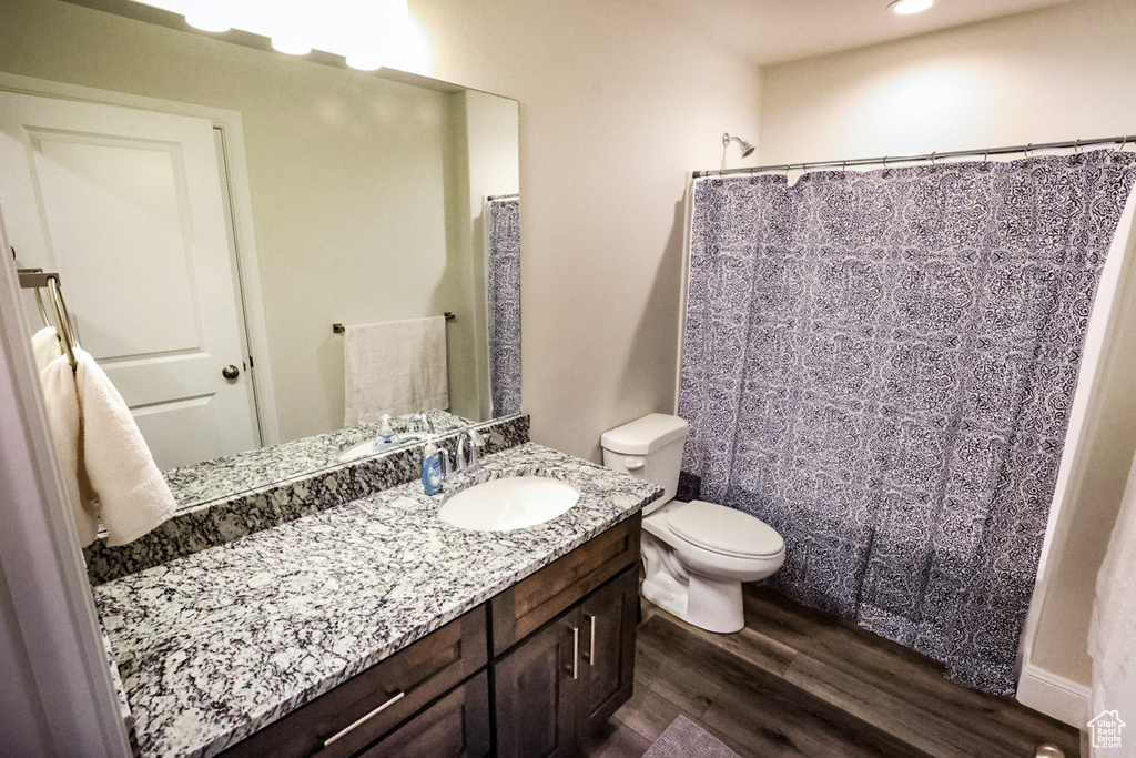 Bathroom featuring recessed lighting, curtained shower, wood finished floors, toilet, and vanity