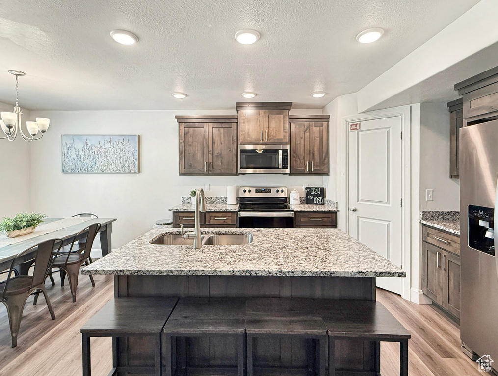 Kitchen featuring appliances with stainless steel finishes, a kitchen breakfast bar, a sink, and light wood-style floors
