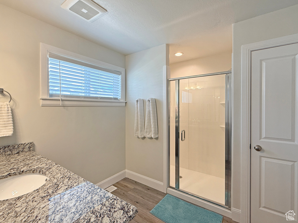 Bathroom featuring wood finished floors, a stall shower, baseboards, visible vents, and recessed lighting