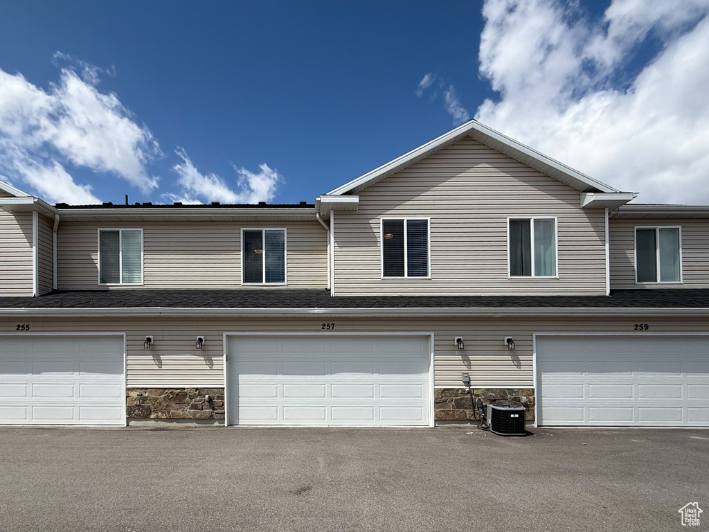 View of front of house featuring an attached garage, central AC, and stone siding
