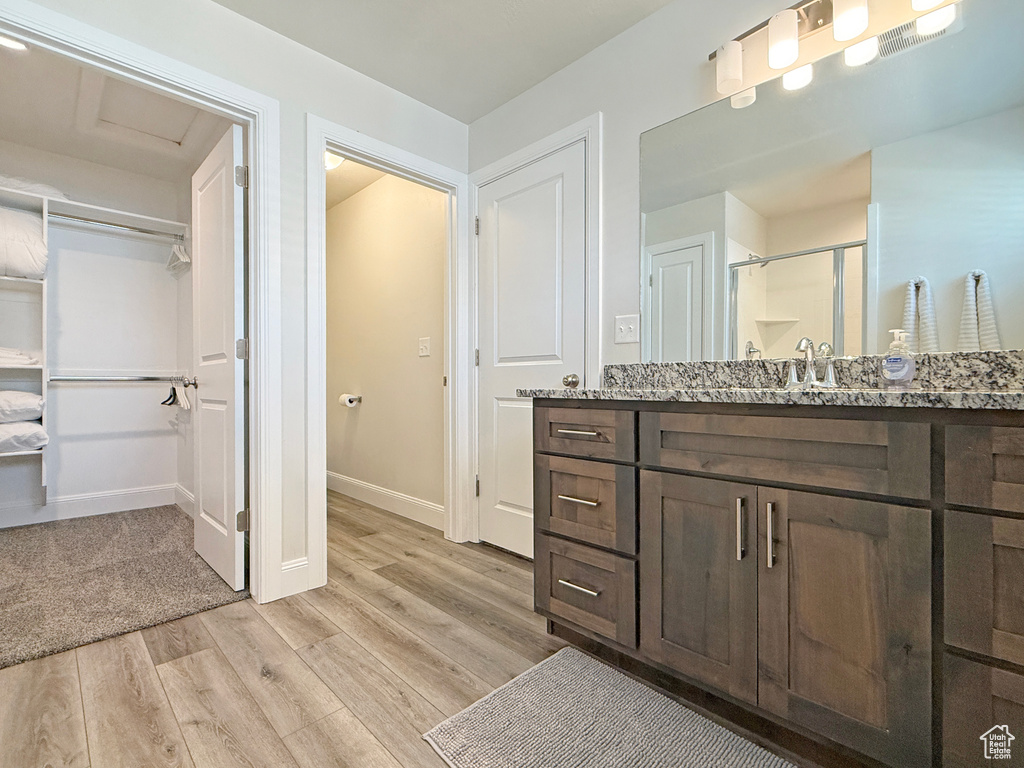 Full bathroom featuring a shower stall, wood finished floors, a spacious closet, vanity, and baseboards