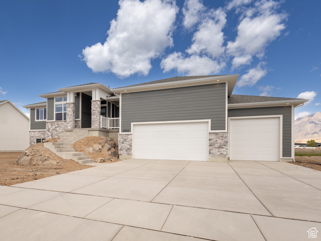 Prairie-style house featuring an attached garage, stone siding, and concrete driveway